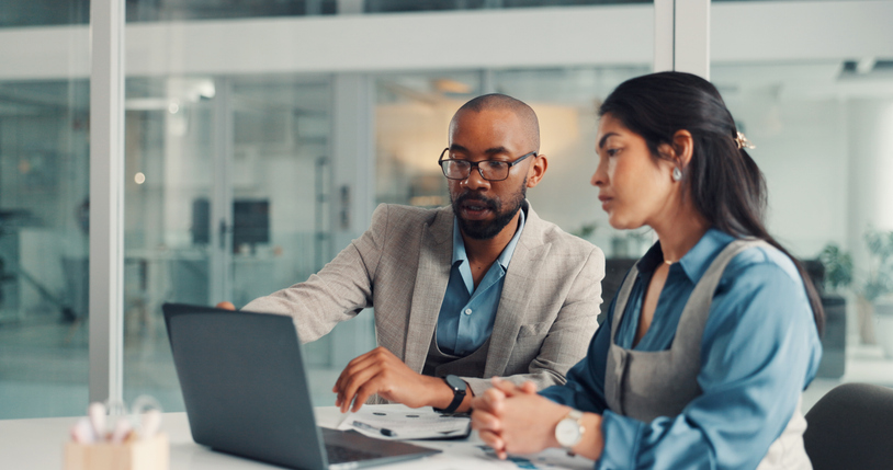 Two colleagues working through a plan together at a laptop